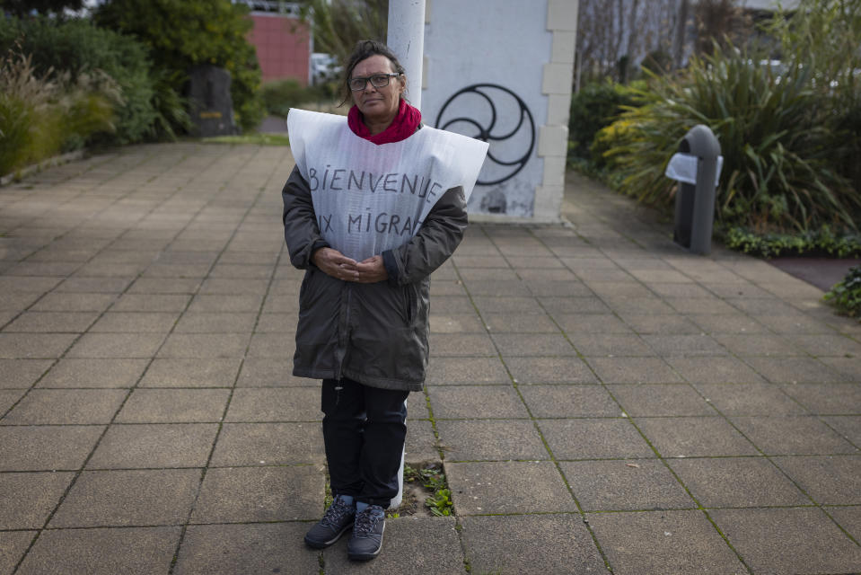 A person in favor of welcoming migrants observes people demonstrating in Saint-Jean-de-Monts, on Saturday Nov. 4, 2023, at the call of the far-right group against the reception in the town of 15 migrants. The small movement known as the Vendee Rally, calls for farmers and fishermen to protest immigrants and foreign imports. (AP Photo/Jeremias Gonzalez)