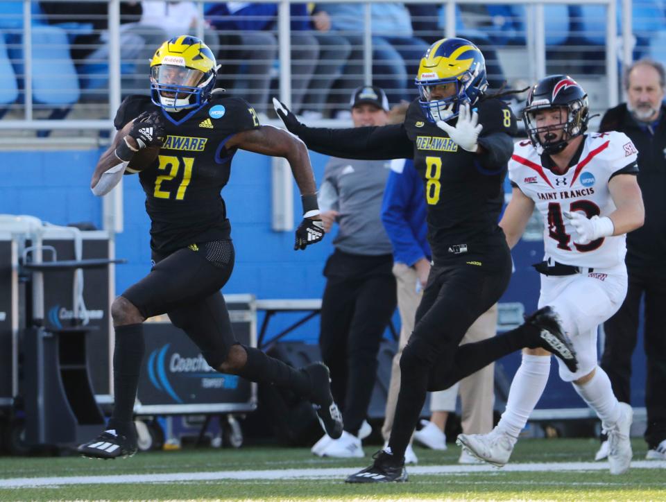 Delaware running back Marcus Yarns (21) has receiver Chandeer Harvin as an escort as he runs ahead of Saint Francis linebacker Mercury Swaim in the second quarter of the opening round of the NCAA FCS tournament at Delaware Stadium, Saturday, Nov. 26, 2022.