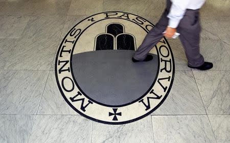 A man walks on a logo of the Monte Dei Paschi Di Siena bank in Rome, Italy September 24, 2013. REUTERS/Alessandro Bianchi/Files