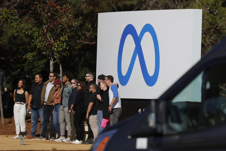 Facebook employees gather in front of a sign displaying a new logo and the name &#39;Meta&#39; in front of Facebook headquarters on October 28, 2021 in Menlo Park, California. (Photo by Justin Sullivan/Getty Images)