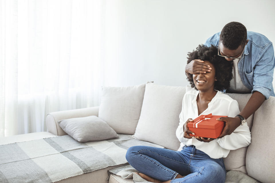 Young couple with gift box hugging at home. Valentine's Day concept. Happy couple in love with. A young loving couple celebrating Valentine's Day at the home. Lovers give each other gifts. Romance home for Valentine's Day- concept