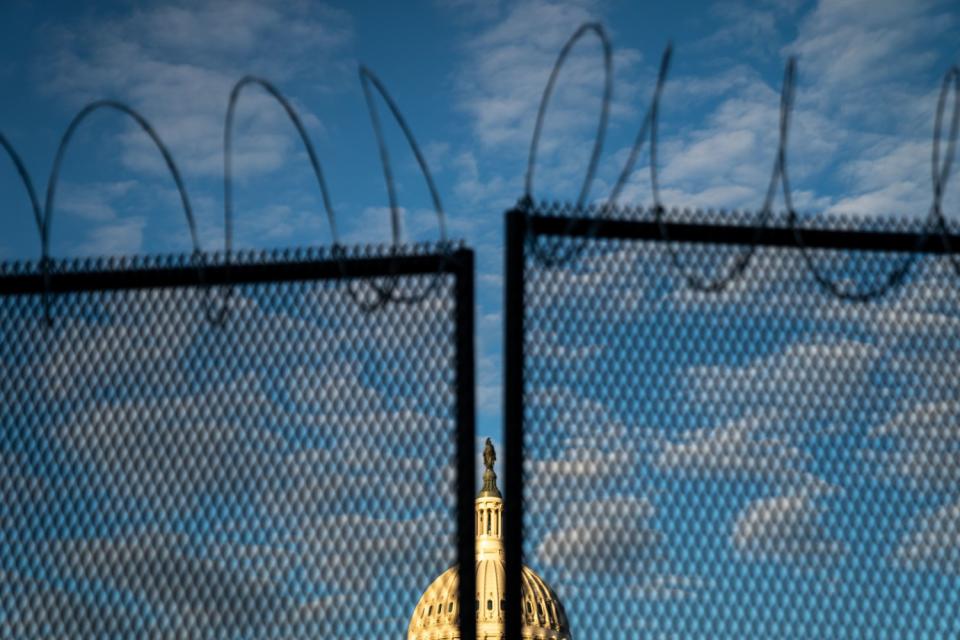 Barbed wire is seen atop security fencing, with the dome of the U.S. Capitol Building Saturday.