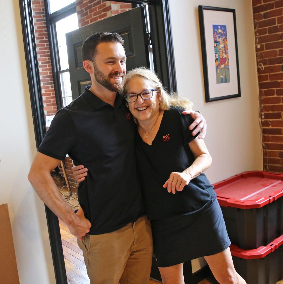 Julie Lapham, founder and chief executive officer at Popzup Popcorn, gets a hug from her son, Nolan, chief operating officer, Thursday, Oct. 5, 2023, as their new location in Somersworth.