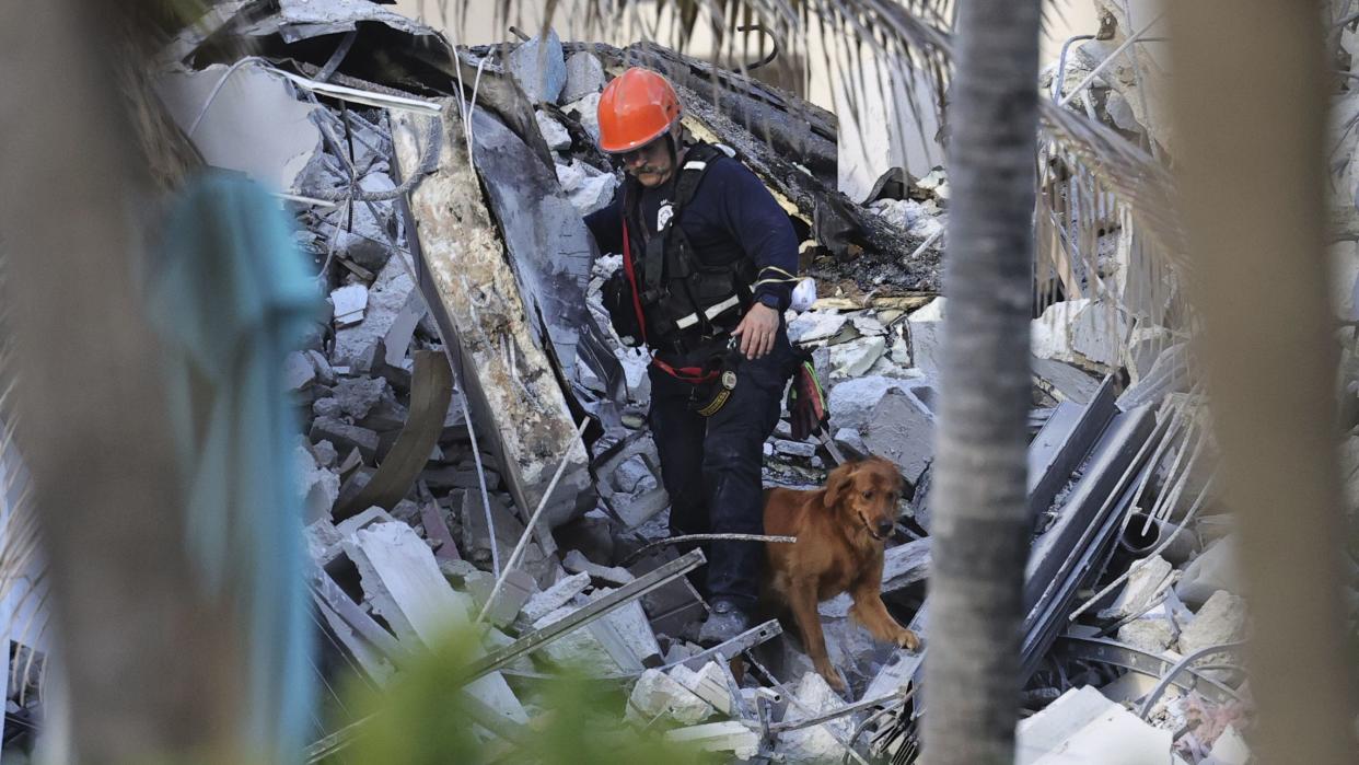 Fire rescue personnel conduct a search and rescue with dogs through the rubble of the Champlain Towers South Condo after the multistory building partially collapsed in Surfside, Fla., Thursday, June 24, 2021.