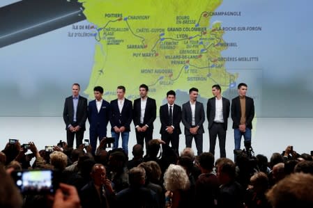 Cyclists pose in front of the map of the 2020 Tour de France cycling race after a news conference in Paris