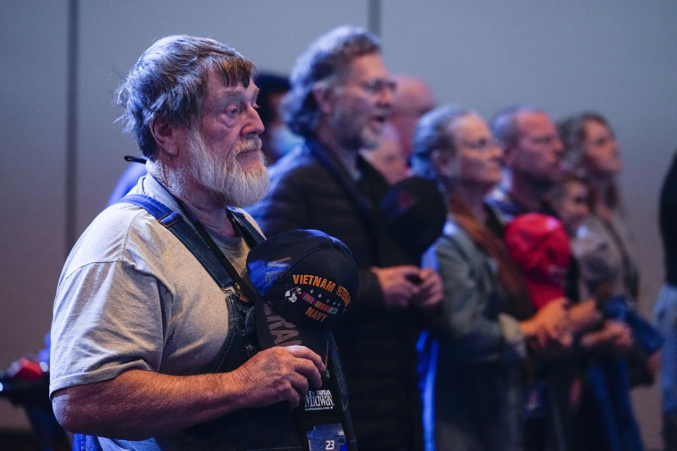 Attendees to the National Rifle Association Convention recite the Pledge of Allegiance before the start of speeches in Indianapolis, Friday, April 14, 2023. (AP Photo/Michael Conroy)