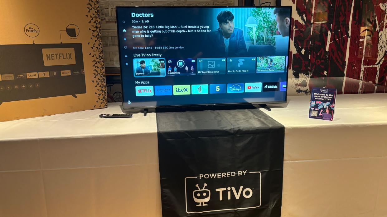  TiVo OS running on a 55-inch TV sitting on a table with a white tablecloth. 