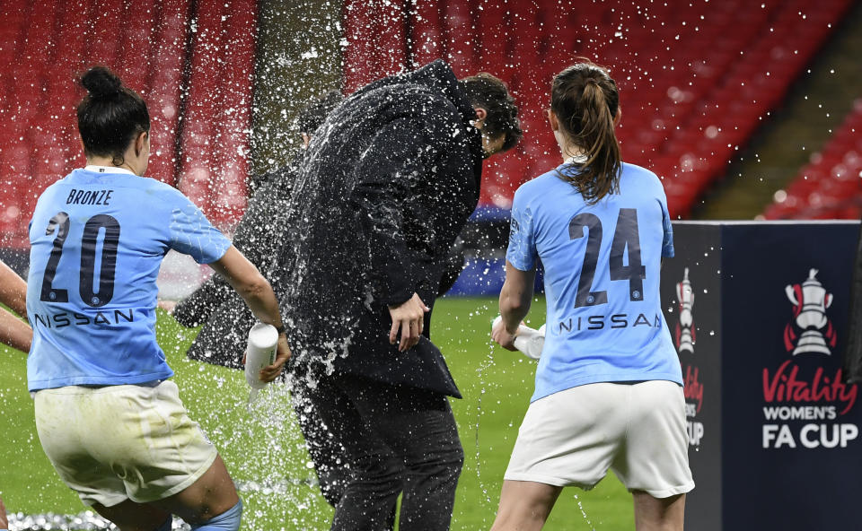 Manchester City's Lucy Bronze, left, and Keira Walsh, right, celebrate with Manchester City's manager Gareth Taylor, center, after winning the Women's FA Cup final soccer match between Everton and Manchester City at Wembley stadium in London, Sunday, Nov. 1, 2020. (Facundo Arrizabalaga/Pool via AP)