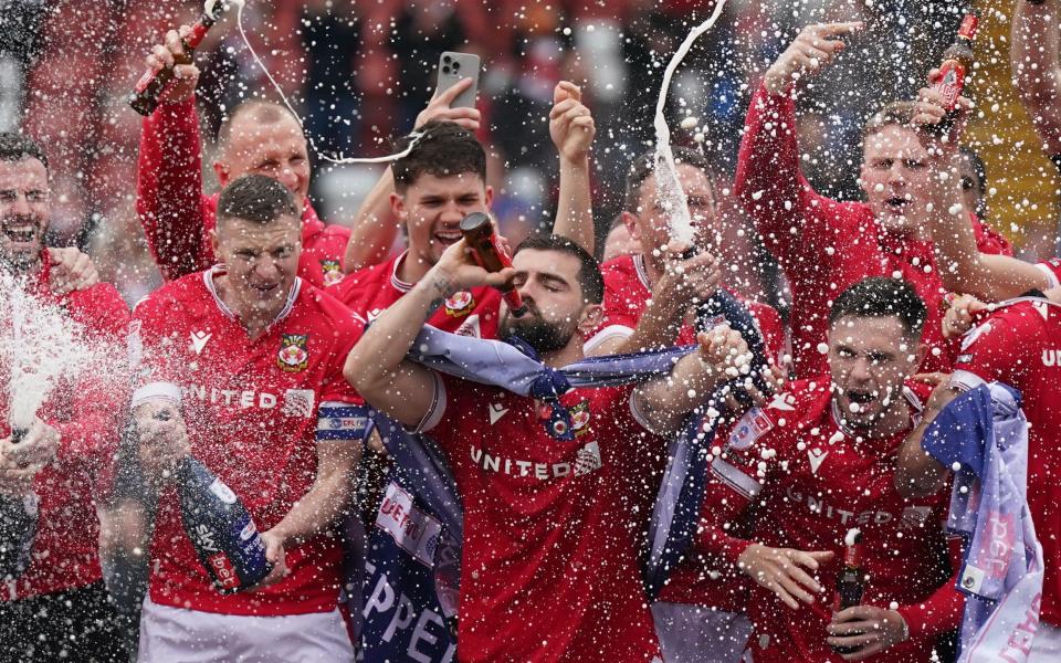 Wrexham players on the pitch celebrating promotion to League One after the final whistle