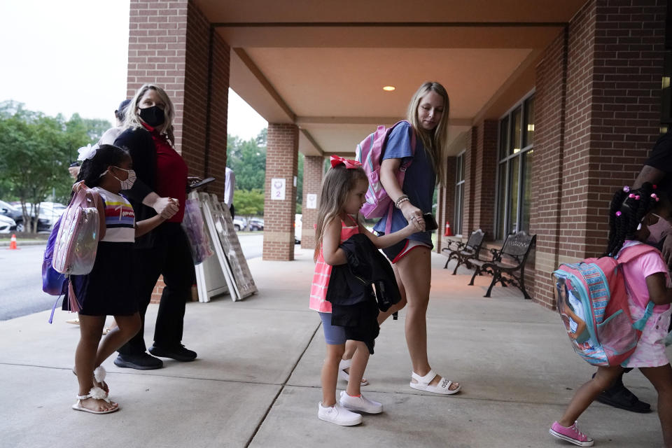 Students and parents walk to class at Tussahaw Elementary school on Wednesday, Aug. 4, 2021, in McDonough, Ga. Schools have begun reopening in the U.S. with most states leaving it up to local schools to decide whether to require masks. (AP Photo/Brynn Anderson)