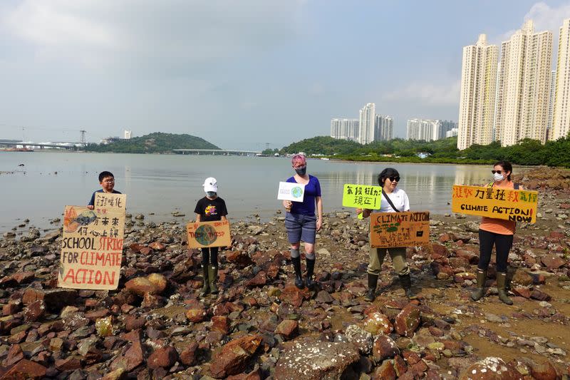 Lance Lau, 11, Elise Hon, 11, Rose Netherton, 36, and other climate activists hold placards as they pose for pictures during a climate strike and a beach clean-up at San Tau Beach on Lantau island in Hong Kong