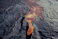 FILE - Molten rock flows from Mauna Loa, located on the south-central part of the island of Hawaii, on March 26, 1984. The ground is shaking and swelling at Mauna Loa, the largest active volcano in the world, indicating that it could erupt. Scientists say they don't expect that to happen right away but officials on the Big Island of Hawaii are telling residents to be prepared in case it does erupt soon. (AP Photo/File)