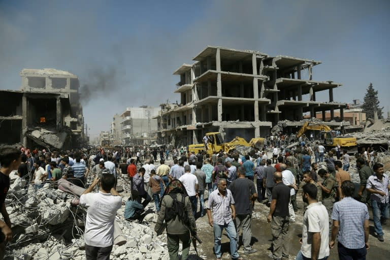 People gather at the site of a bomb attack in the northeastern Syrian city of Qamishli on July 27, 2016 which killed at least 44 people, state media said