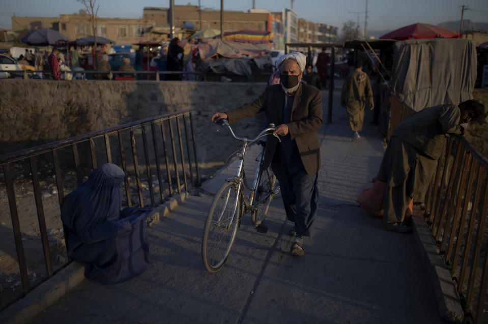 An Afghan woman begs at a market in Kabul, Afghanistan, Tuesday, Oct. 12, 2021. (AP Photo/Ahmad Halabisaz)