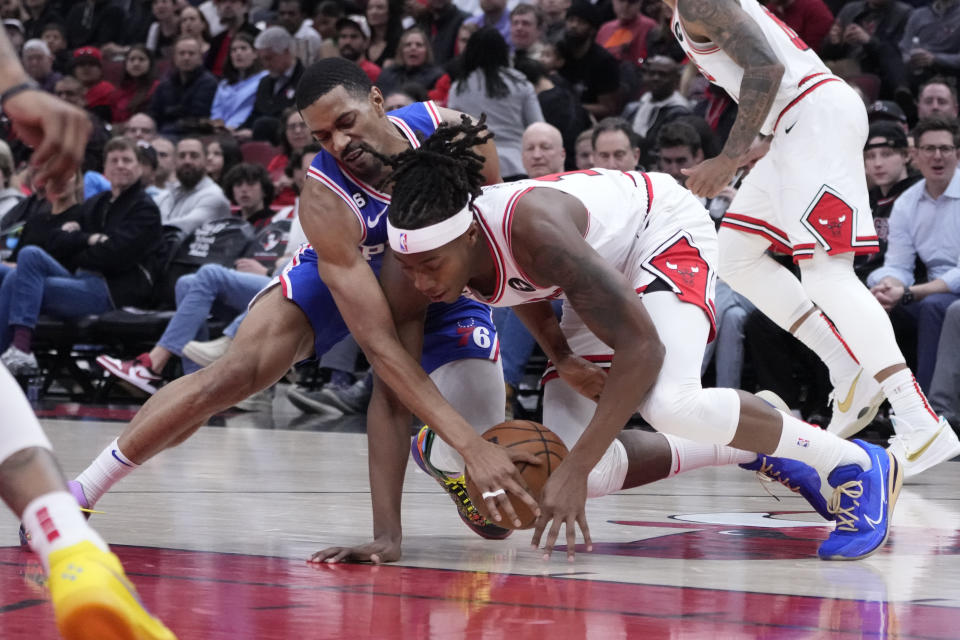 Philadelphia 76ers' De'Anthony Melton, left, and Chicago Bulls' Ayo Dosunmu battle for a loose ball during the first half of an NBA basketball game Wednesday, March 22, 2023, in Chicago. (AP Photo/Charles Rex Arbogast)