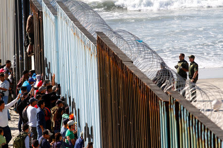 Migrants, part of a caravan of thousands trying to reach the U.S., look through the border fence between Mexico and the United States, in Tijuana, Mexico November 14, 2018. REUTERS/Jorge Duenes