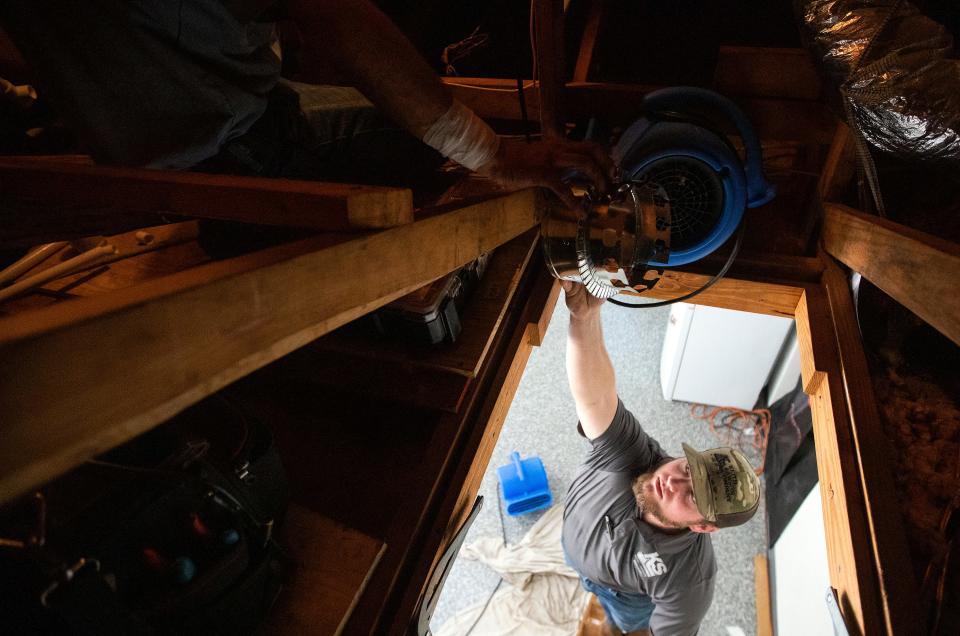 Josh Brown hands supplies to Dillon Kent as the Keith Lawson Services team works on a residential air conditioning unit on Thursday, June 16, 2022 in Tallahassee, Fla. 