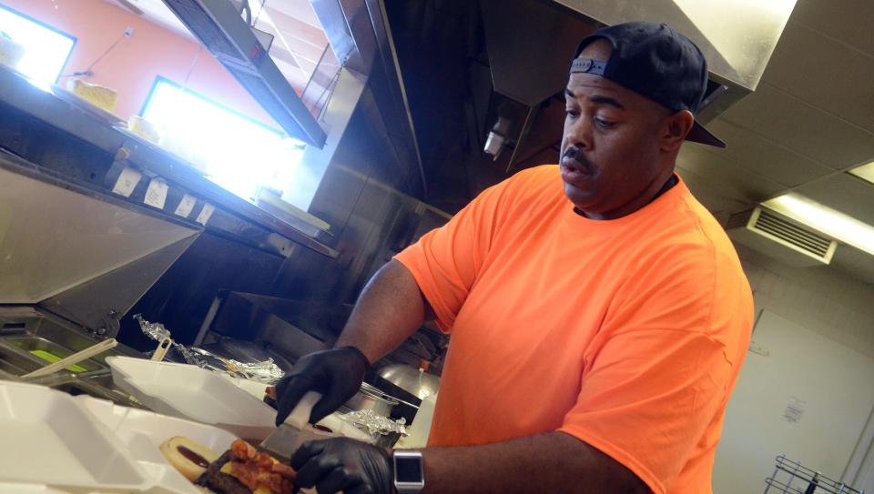 Former Adelanto Mayor Pro Tem Jermaine Wright prepares a burger at his restaurant, Fat Boyz Grill, in 2016. Wright was sentenced to 5 years in federal prison for accepting a bribe for his political influence and hiring a man to burn down his restaurant.