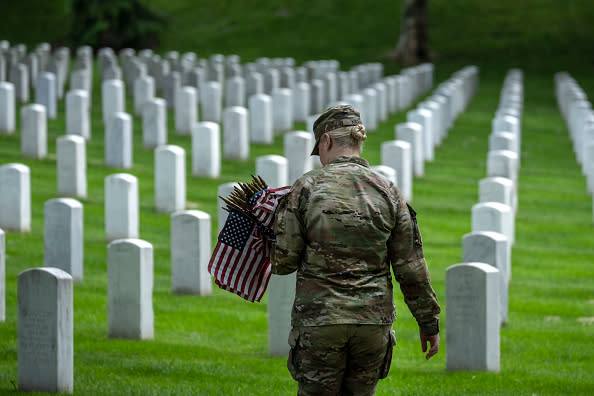 A member of the 3rd U.S. Infantry Regiment places flags at the headstones of U.S. military personnel buried at Arlington National Cemetery, in preparation for Memorial Day.