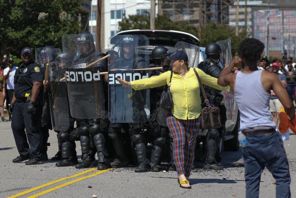 Dawn Bradley stands between police and an angry demonstrator during a protest at the City of Columbia Police headquarters. Crowds gathered for a peaceful rally to protest the killing of George Floyd escalated into a riot with groups breaking into businesses and burning police cars in the Columbia Vista.