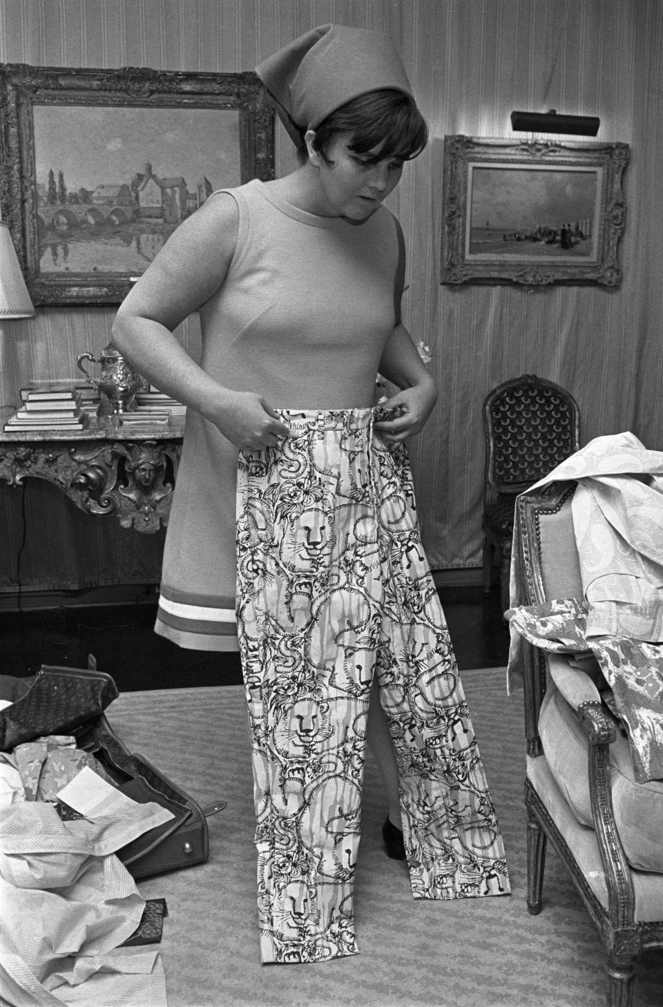 Fashion designer Lily Pulitzer, wearing a headscarf and sleevless top, being interviewed with her printed fabrics in her studio