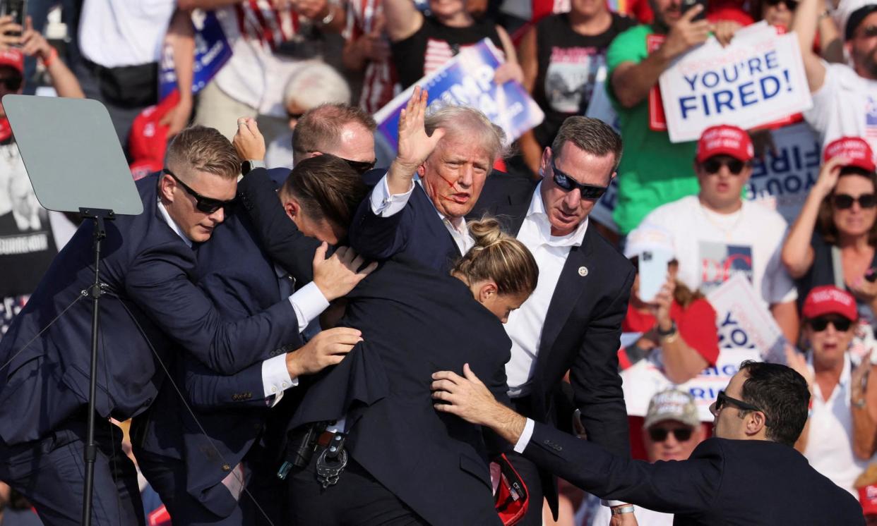 <span>Secret Service agents flock around Trump after a bullet grazed his ear during a campaign rally in Butler, Pennsylvania, on 13 July.</span><span>Photograph: Brendan McDermid/Reuters</span>