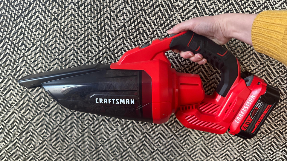 the author holding the red craftsman hand vacuum