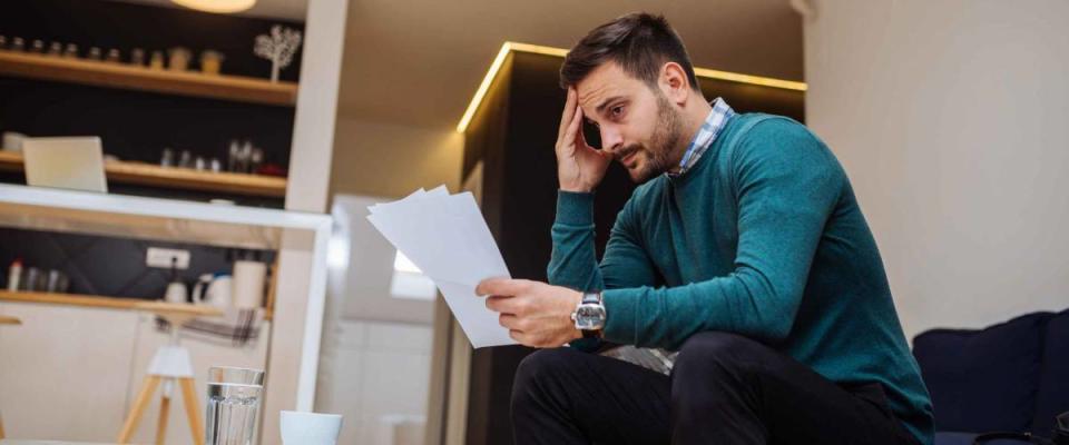 Handsome businessman looking at bills at home.