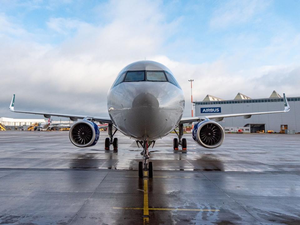 An Airbus A321neo sitting on the ramp with an Airbus sign in the background.