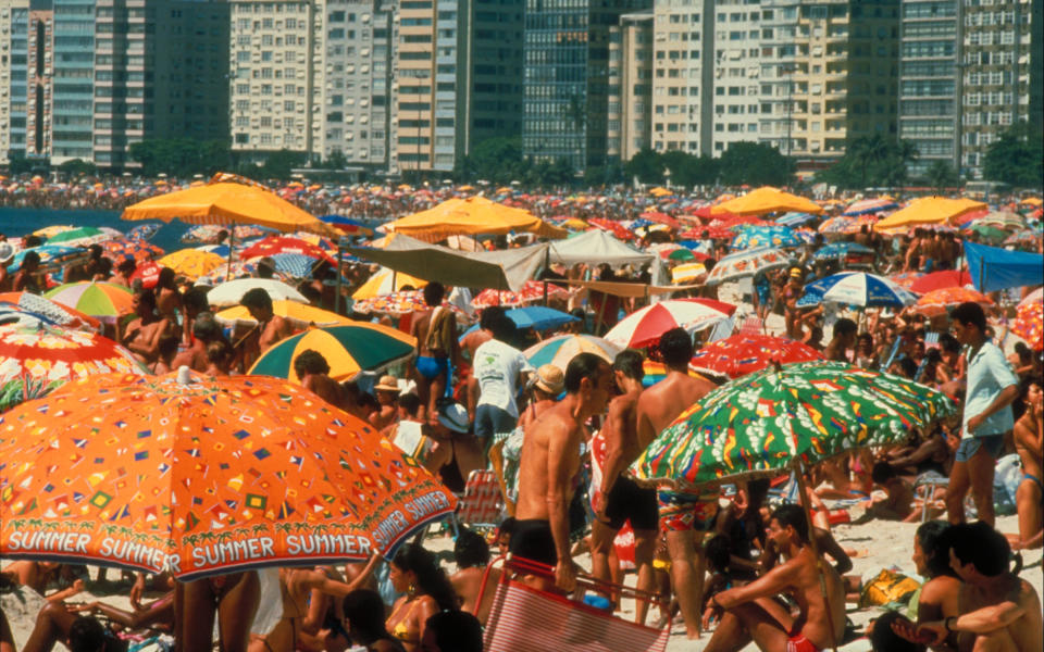 An electric orange beach umbrella on this crowded crescent of sand says it all: summers are synonymous with long afternoons by the water.