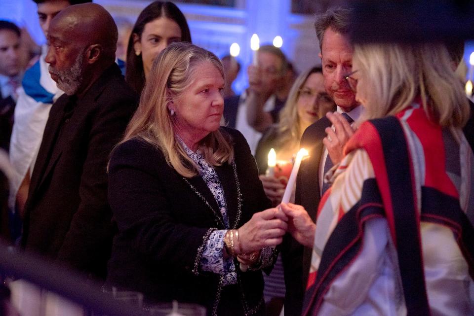 Palm Beach Mayor Danielle Moore lights a candle as hundreds of community members attend the 'We Stand with Israel' event Tuesday night at Palm Beach Synagogue. The event was held to show support for Israel following Saturday's attack by Hamas that left more than 1,200 dead, including at least 14 Americans, U.S. officials said.