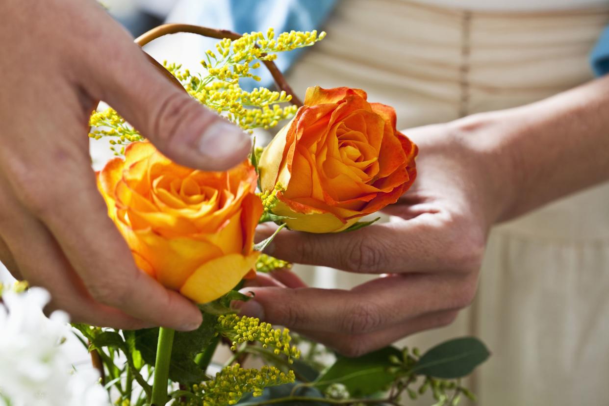 hands arranging fresh cut flowers in vase