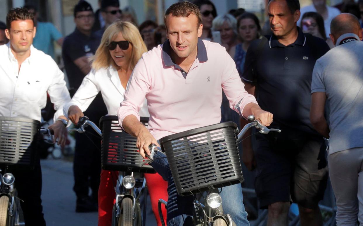 French President Emmanuel Macron and his wife Brigitte ride their bicycles as they leave their home in Le Touquet - REUTERS