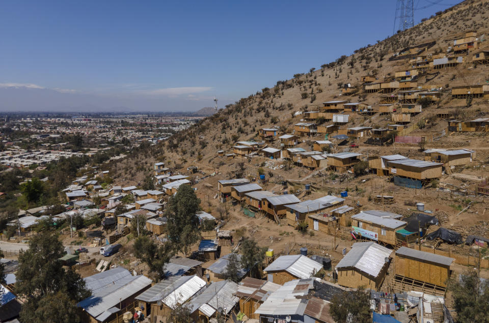 Homes stand on the side of a hill in an unpaved area named "Bosque Hermoso," or Beautiful Forest, where migrants from Haiti, Peru and Colombian settled in Lampa, Chile, Friday, Oct. 1, 2021. The situation of the migrants became more difficult in 2018 when Chile’s government issued a decree requiring that Haitians obtain a consular visa before traveling to Chile, then last April enacted a new migration law that seeks to prevent the irregular entry of foreigners. (AP Photo/Esteban Felix)