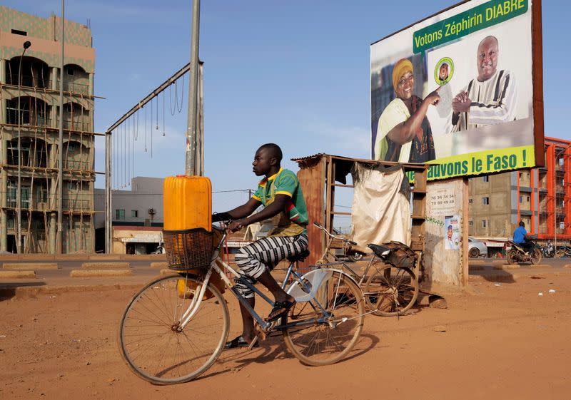 A man rides a bicycle past a campaign poster of presidential candidate Zephirin Diabre in Ouagadougou