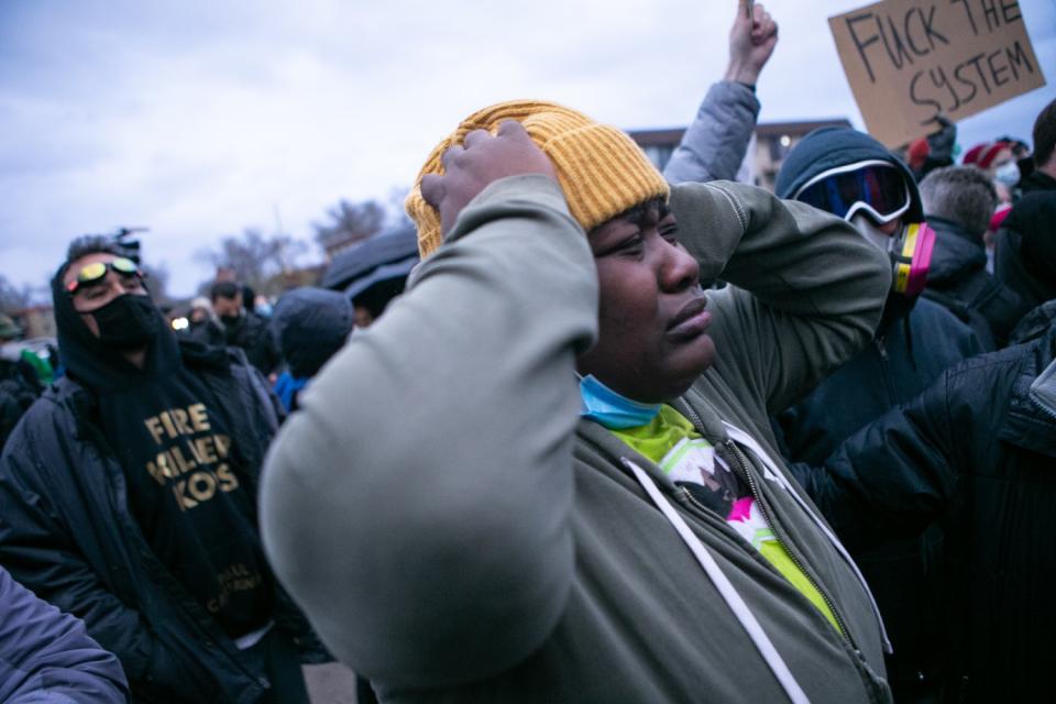 A woman grimaces and puts both hands on her head amid a crowd of protesters