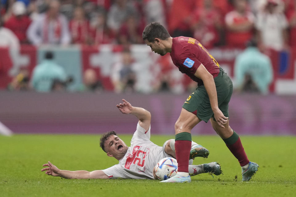 Portugal's Raphael Guerreiro, right, fights for the ball with Switzerland's Xherdan Shaqiri during the World Cup round of 16 soccer match between Portugal and Switzerland, at the Lusail Stadium in Lusail, Qatar, Tuesday, Dec. 6, 2022. (AP Photo/Darko Bandic)