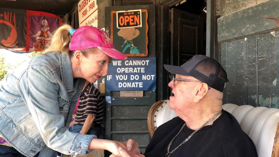 The Social Butterfly columnist Kristi K. Higgins gets her palm read by former Progress-Index columnist Jimmy Olgers on the Olgers Store Museum porch in Sutherland on May 6, 2023.