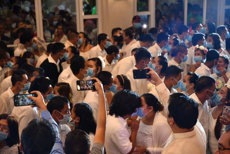 Filipino couples kiss while wearing their face masks in a government-sponsored mass wedding in Bacolod City