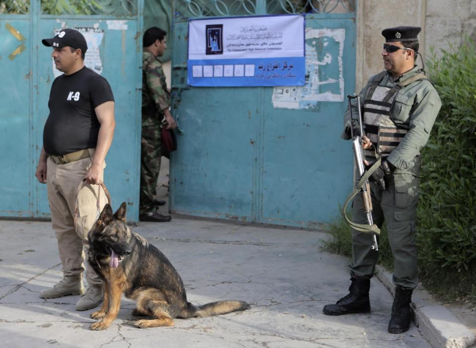 Security forces and K-9 dog stand guard outside a polling center in Baghdad, Iraq, Monday, April 28, 2014. Amid tight security, some one million Iraqi army and police personnel have started voting for the nation's new parliament. (AP Photo/ Khalid Mohammed)