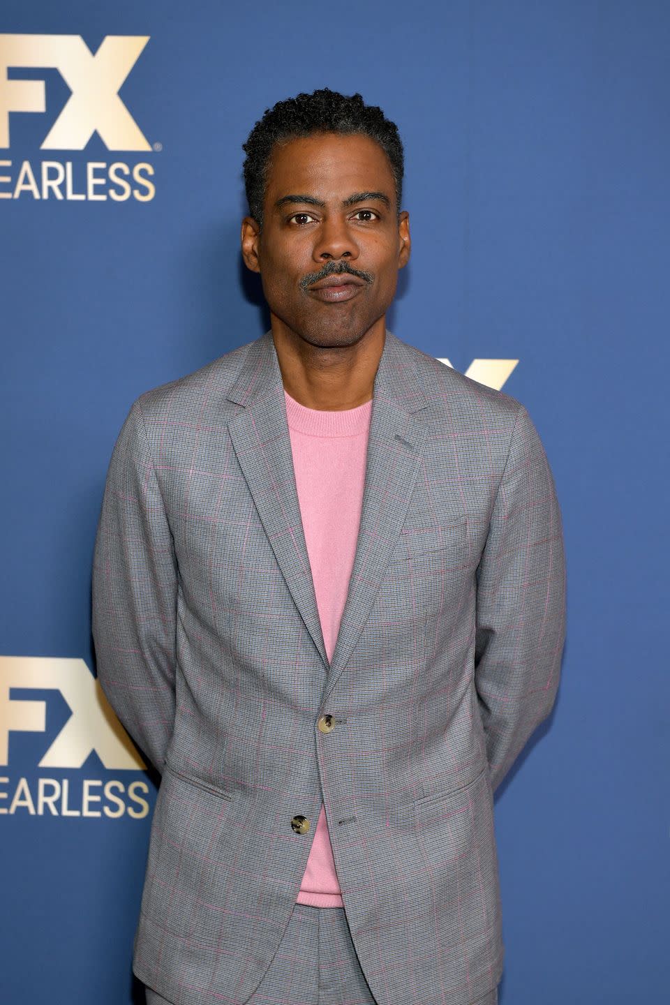 chris rock in a grey suit and pink t shirt