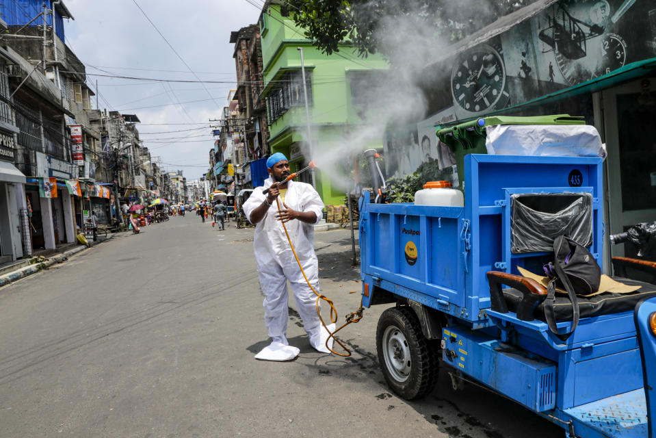 A civic worker sprays sanitizers in front of roadside shops in Kolkata, India, Sunday, Aug. 30, 2020. India has the third-highest coronavirus caseload after the United States and Brazil, and the fourth-highest death toll in the world. (AP Photo/Bikas Das)