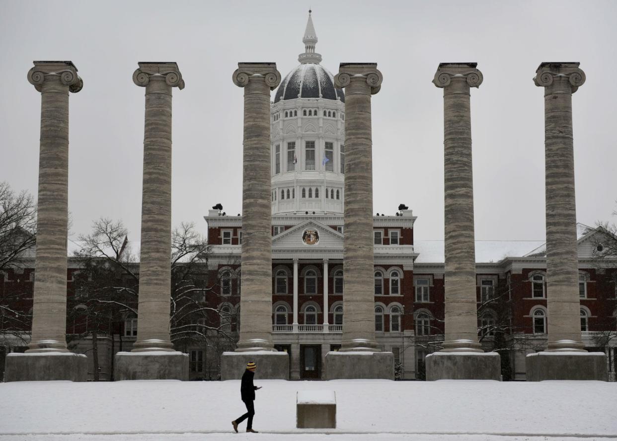 A man walks past the Columns on the Francis Quadrangle as it snows in a Tribune file photo.