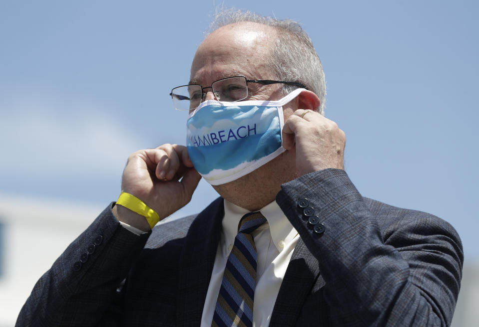 Miami Beach Mayor Dan Gelber adjusts his masks before speaking during a news conference along with other South Florida Mayors, Monday, June 22, 2020, in Miami. More than 100,000 people in Florida have been diagnosed with the coronavirus, state health officials reported Monday, as public health officials reissued advisories urging social distancing and mask wearing. (AP Photo/Wilfredo Lee)