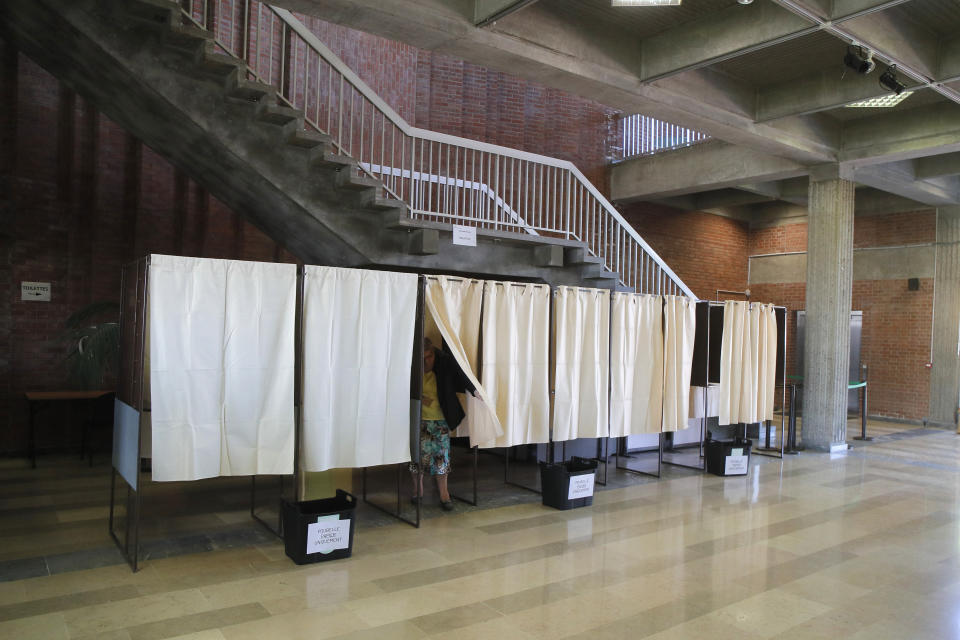 A woman leaves a voting booth before voting for the first round of the parliamentary elections, Sunday, June 12, 2022 in Lille, northern France. French voters are choosing lawmakers in a parliamentary election as President Emmanuel Macron seeks to secure his majority while under growing threat from a leftist coalition. More than 6,000 candidates, ranging in age from 18 to 92, are running for 577 seats in the National Assembly in the first round of the election. (AP Photo/Michel Spingler)