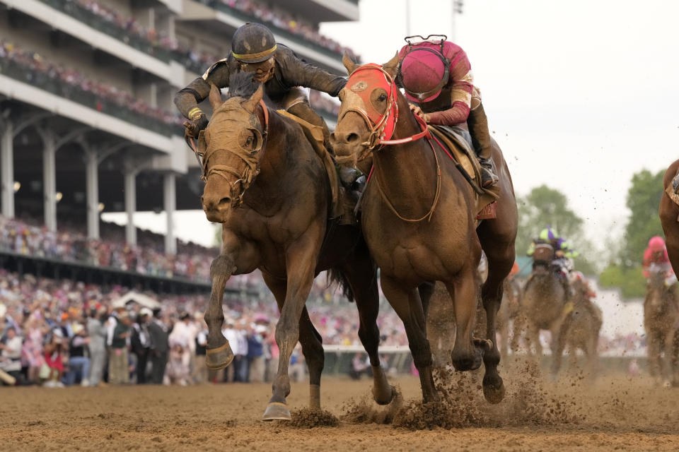 Jockey Tyler Gaffalione riding Sierra Leone, left, reaches toward Ryusei Sakai riding Forever Young as they head to the finish line to finish second and third respectively in the 150th running of the Kentucky Derby horse race at Churchill Downs Saturday, May 4, 2024, in Louisville, Ky. (AP Photo/Jeff Roberson)