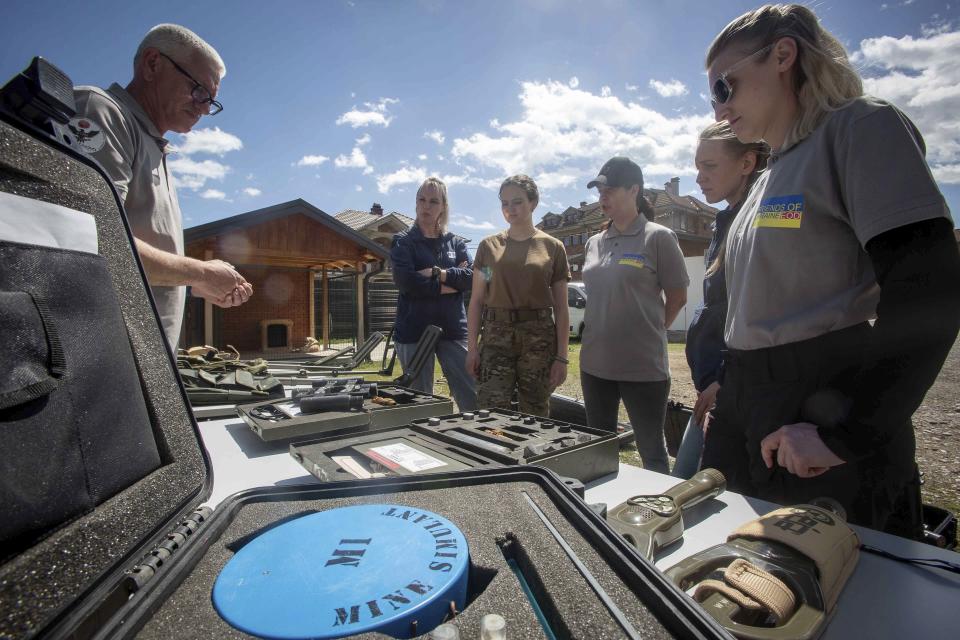 Demining instructor Artur Tigani, left, briefs a group of Ukrainian female emergency services personnel for specialist training in explosive ordnance disposal and survey training in the western Kosovo city of Peja on Monday, April 25, 2022. Six Ukrainian women have started to be trained in Kosovo to dispose of explosive ordnance that have contaminated their country invaded by Russia. (AP Photo/Visar Kryeziu)