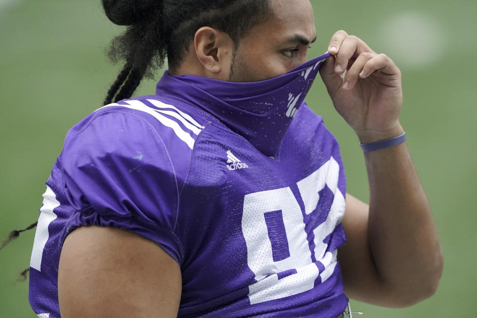 Washington defensive lineman Noa Ngalu pulls up his mask at the start of NCAA college football practice, Friday, Oct. 16, 2020, in Seattle. (AP Photo/Ted S. Warren)