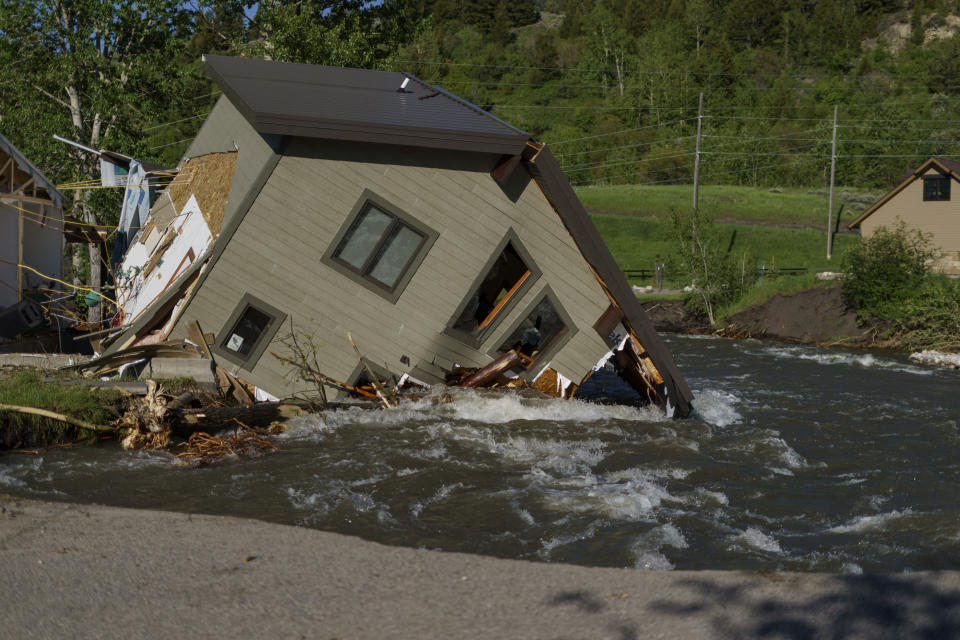FILE - A house sits in Rock Creek after floodwaters washed away a road and a bridge in Red Lodge, Mont., June 15, 2022. Young plaintiffs who are challenging the constitutionality of a Montana policy that does not require state agencies to consider the effect of greenhouse gas emissions in issuing permits for fossil fuel development, argue the state is not doing enough to prevent climate change that leads to weather extremes. The scheduled two-week trial begins Monday, June 12, 2023, in Helena, Mont. (AP Photo/David Goldman, File)