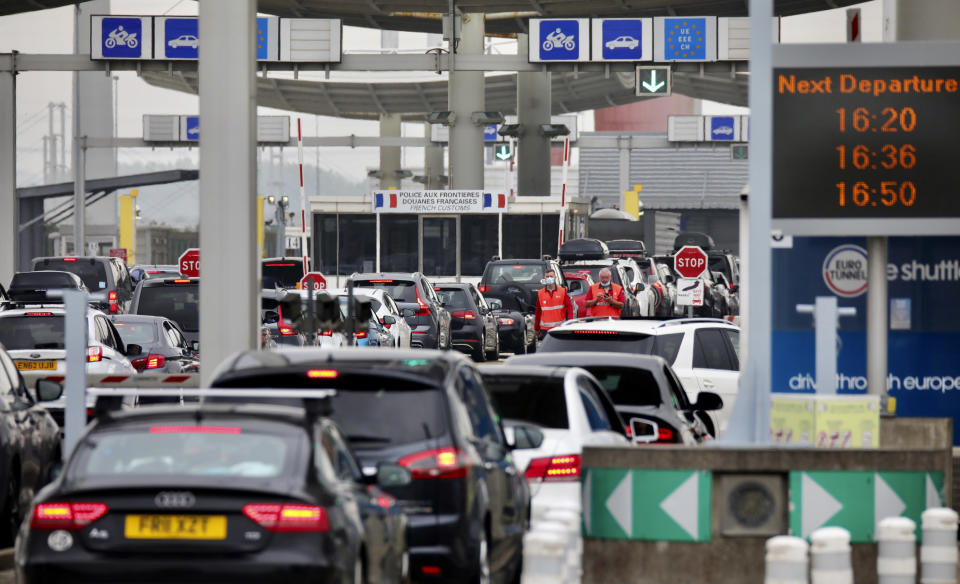 People queue in line to check-in for the Euro Tunnel train to the U.K. in Coquelles, France, Friday Aug.14, 2020. British holiday makers in France were mulling whether to return home early Friday to avoid having to self-isolate for 14 days following the U.K. government's decision to reimpose quarantine restrictions on France amid a recent pick-up in coronavirus infections. (AP Photo/Olivier Matthys)